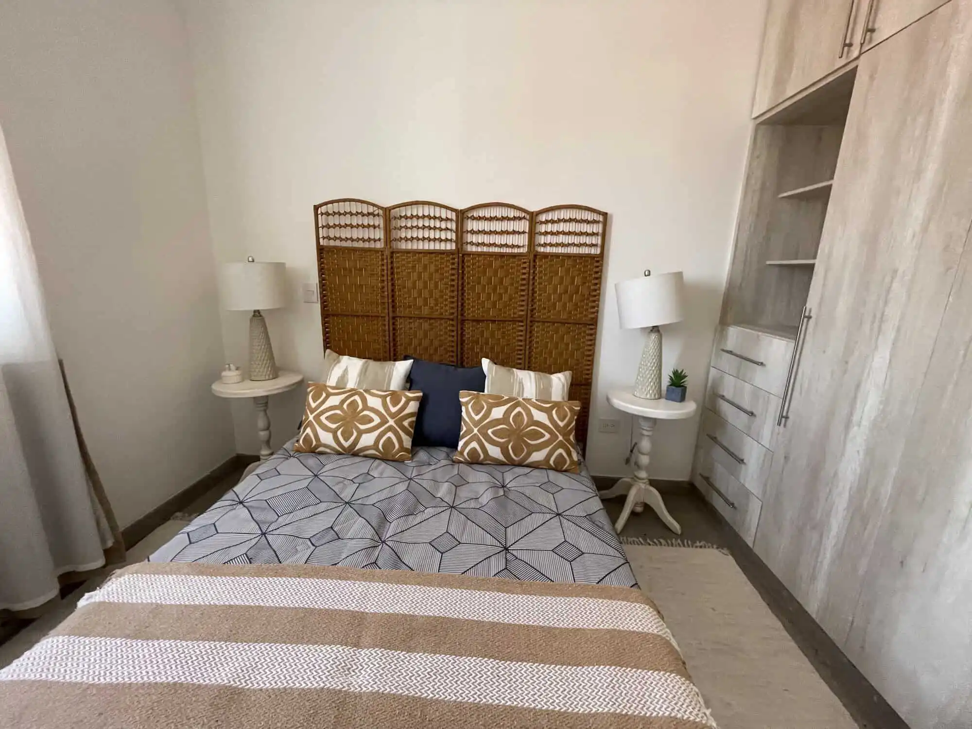 Cozy bedroom with modern decor and rattan headboard in Santo Domingo home.