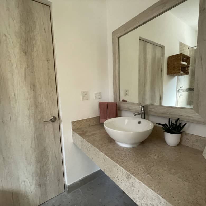 Bathroom with a round vessel sink and large mirror in a modern colonial-style home.
