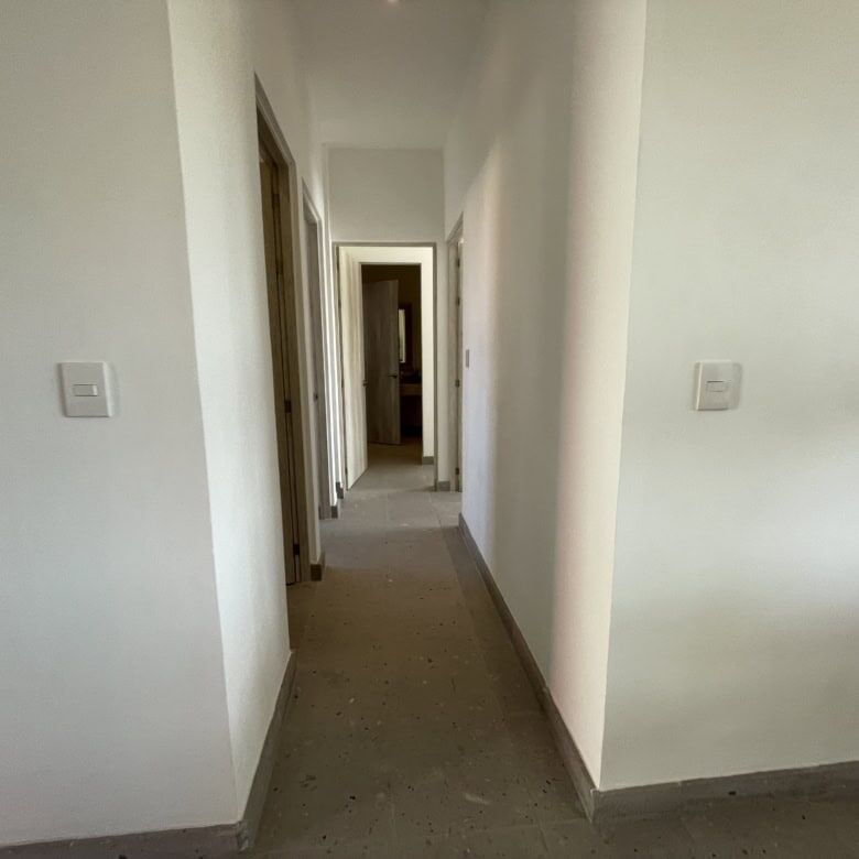 Bright, clean corridor with white walls and wooden door frames.