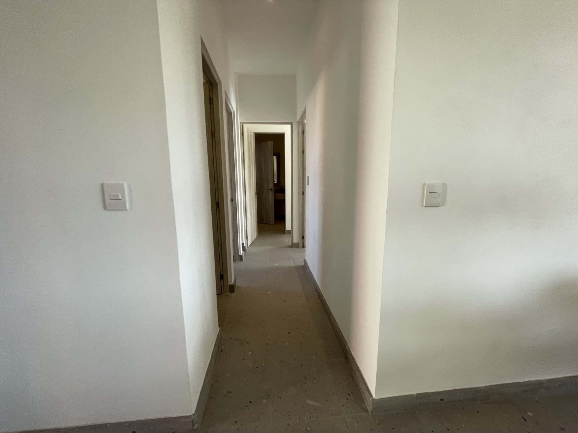 Bright, clean corridor with white walls and wooden door frames.