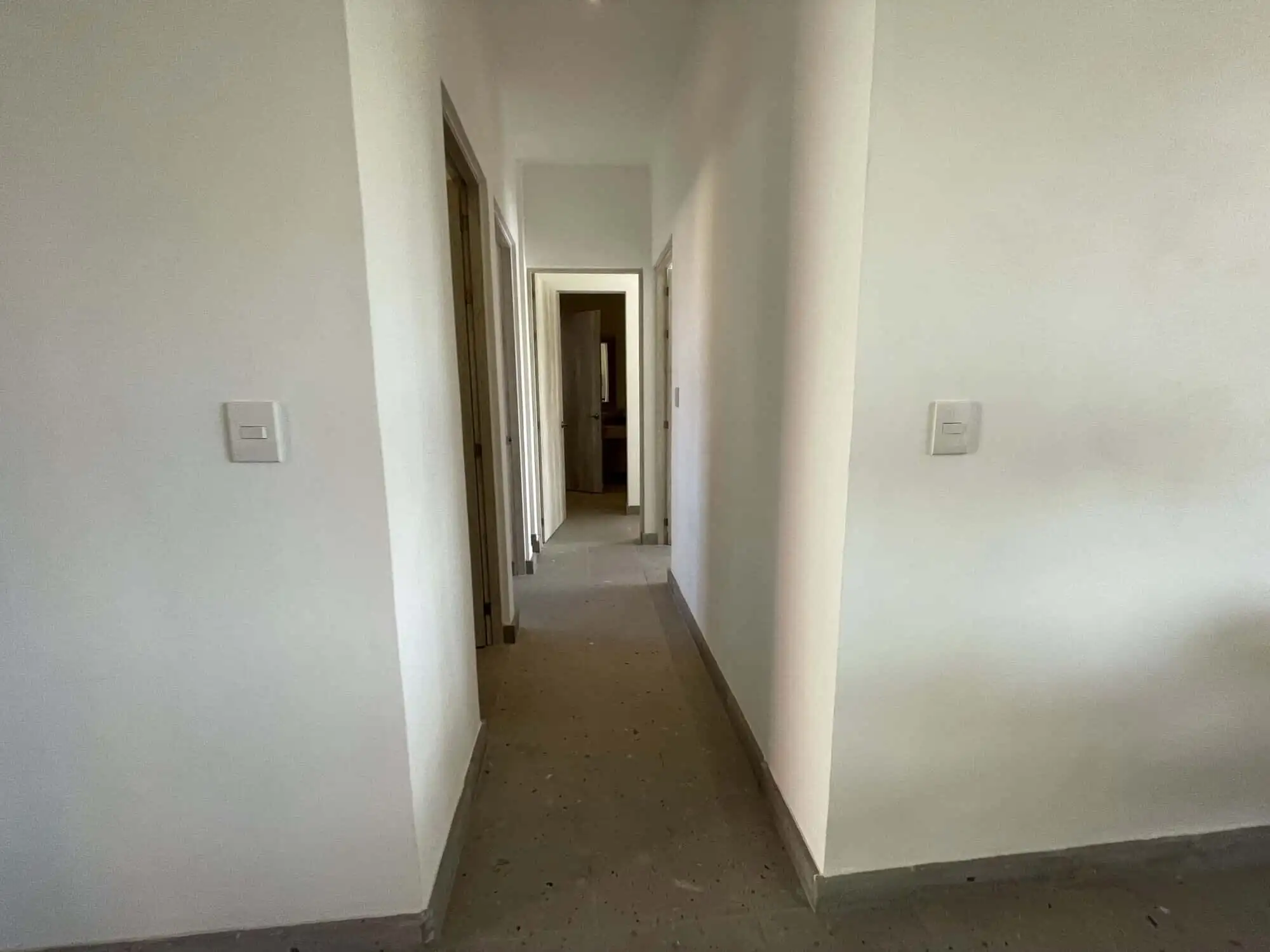 Bright, clean corridor with white walls and wooden door frames.