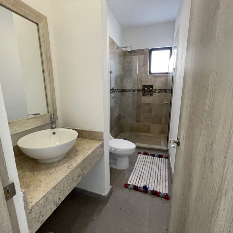 Bright bathroom featuring a stylish sink, toilet, and walk-in shower in a contemporary home.