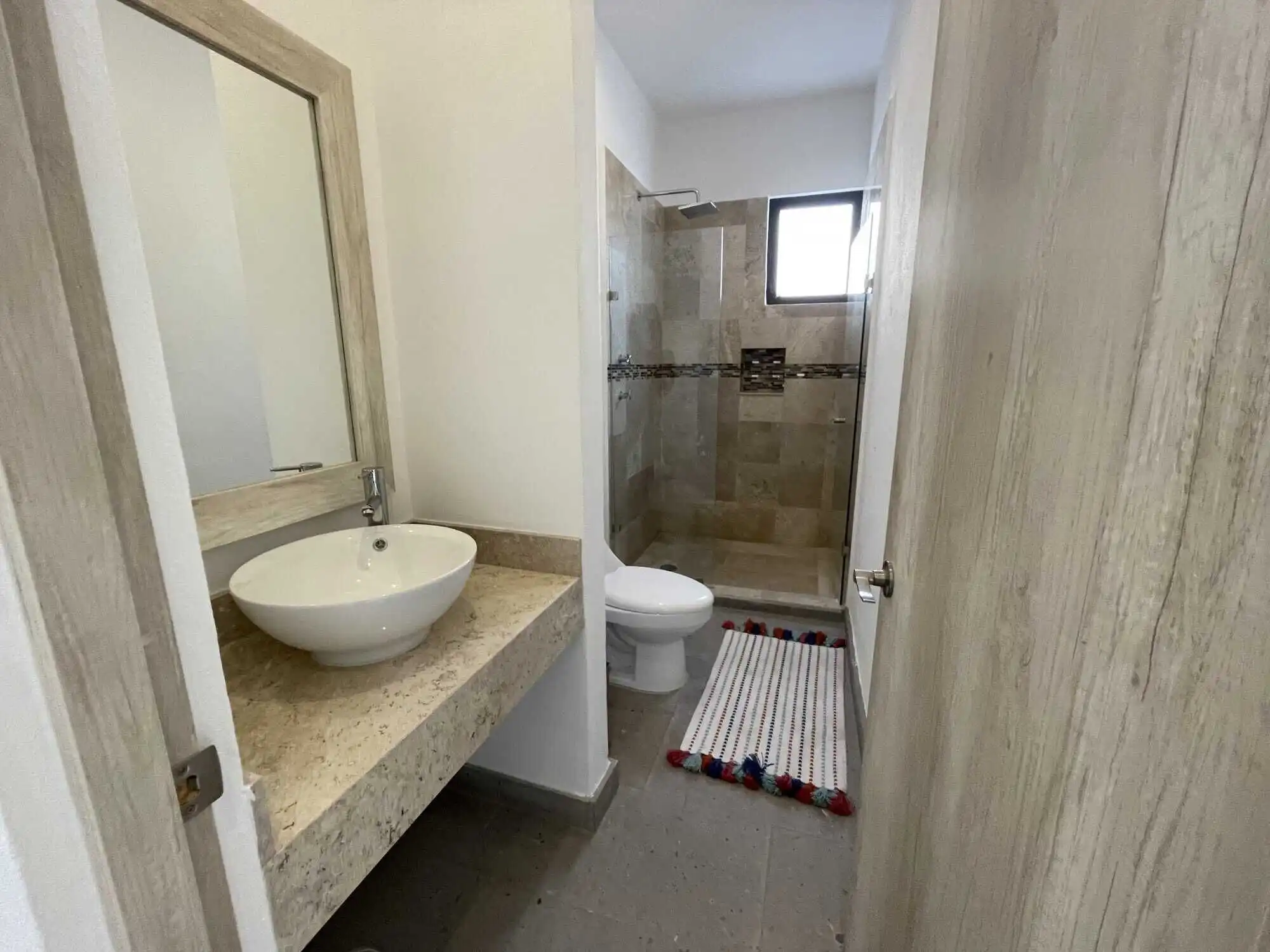 Bright bathroom featuring a stylish sink, toilet, and walk-in shower in a contemporary home.