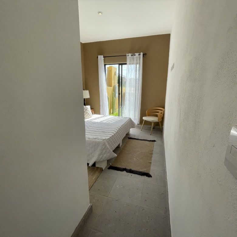 Bright bedroom with large window, cozy decor, and minimalist design.