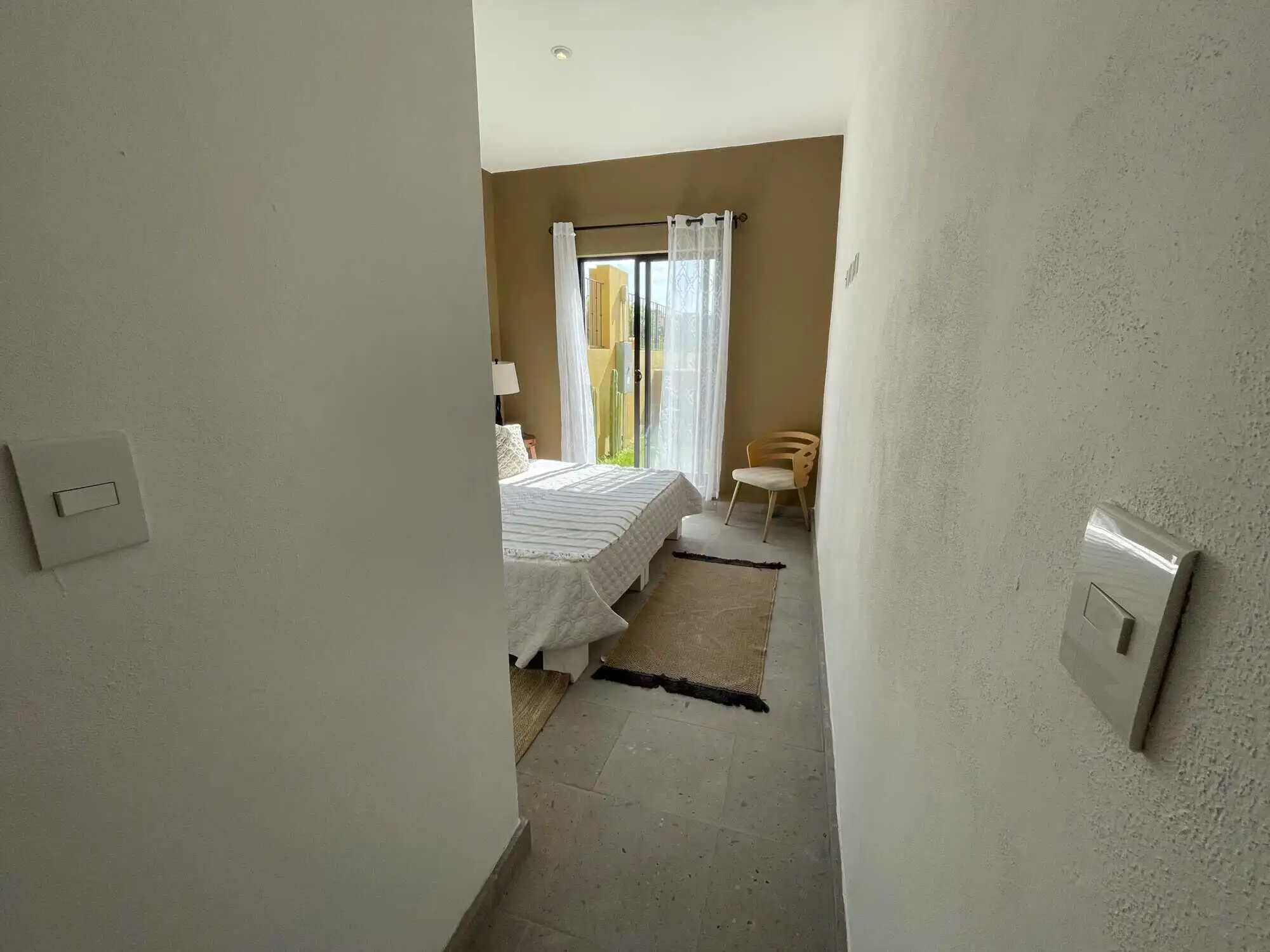 Bright bedroom with large window, cozy decor, and minimalist design.