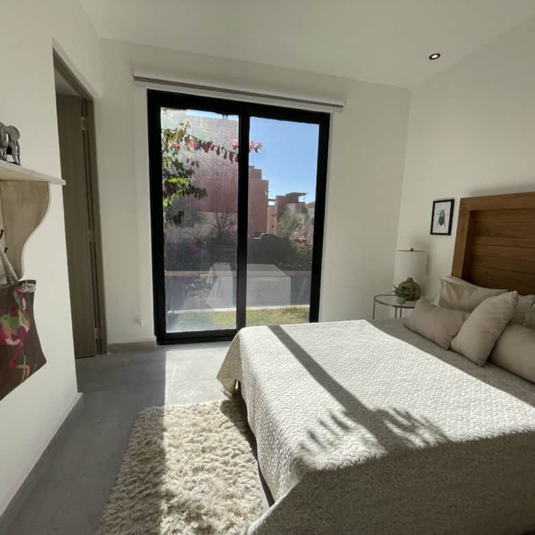Spacious bedroom with natural light, modern decor, and a view of the garden through sliding glass do.