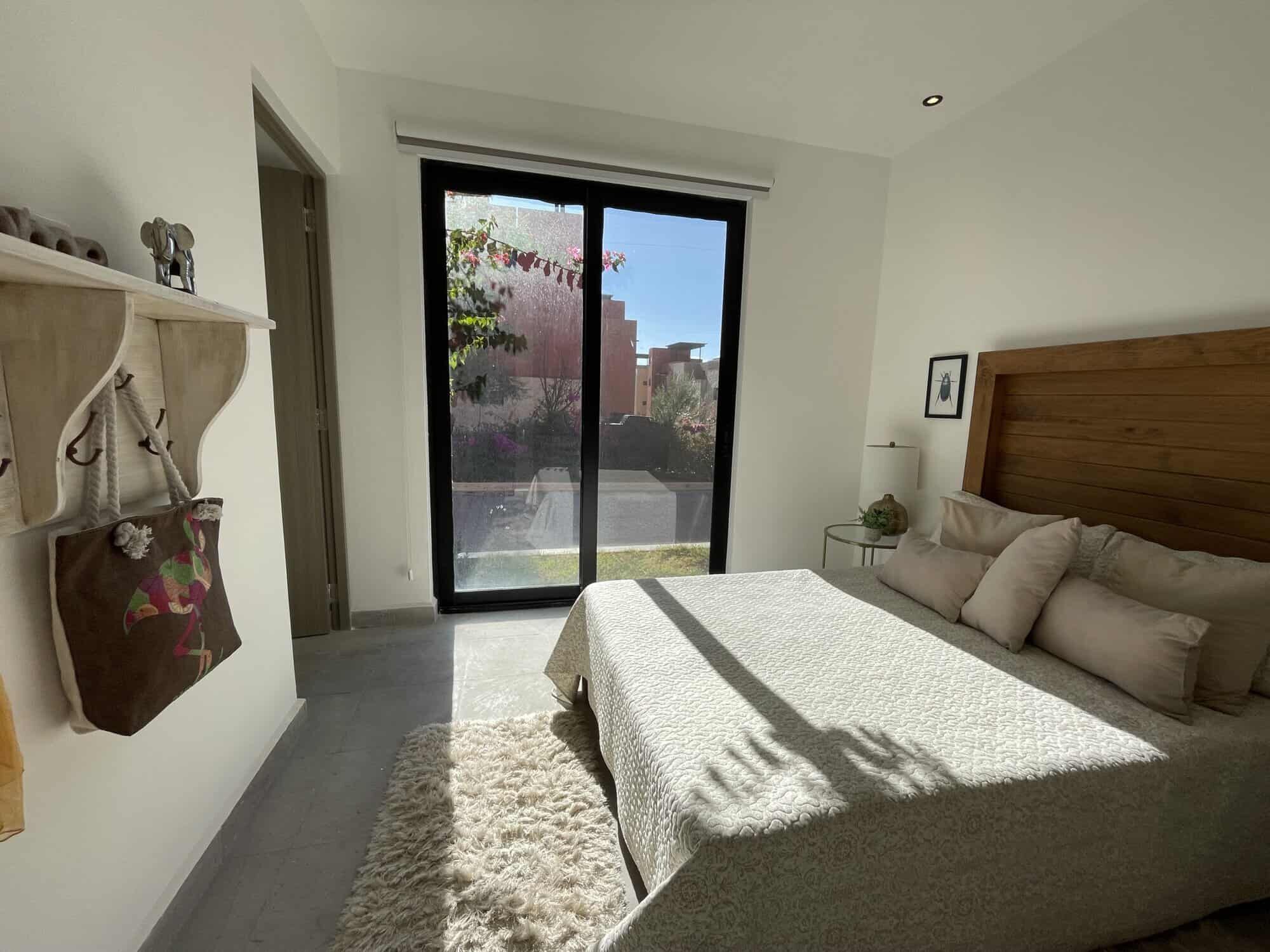 Spacious bedroom with natural light, modern decor, and a view of the garden through sliding glass do.