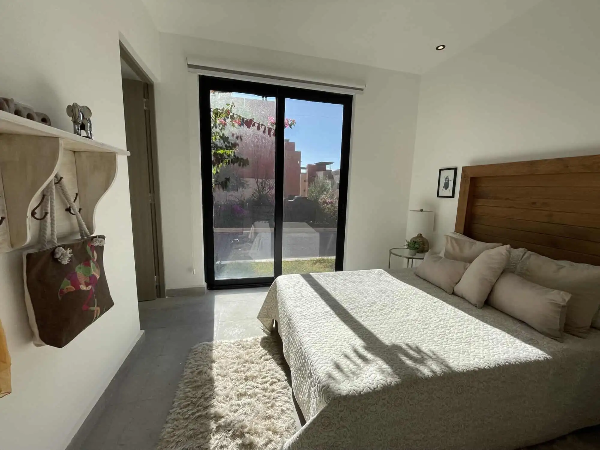 Spacious bedroom with natural light, modern decor, and a view of the garden through sliding glass do.
