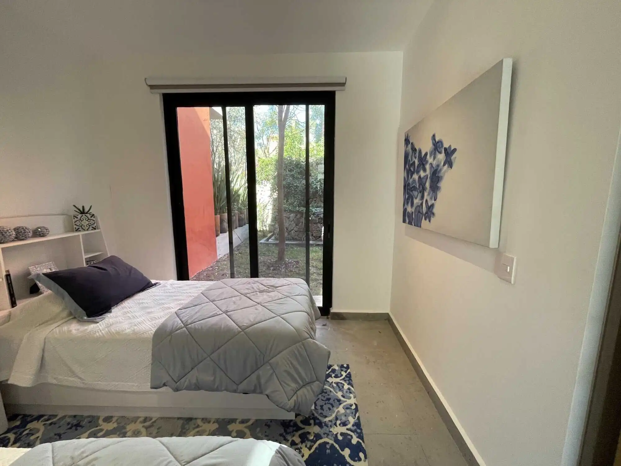 Bright bedroom with large sliding glass door opening to garden.
