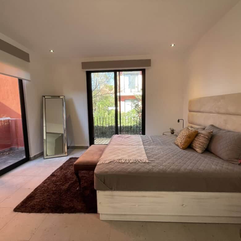 Spacious bedroom with modern decor, large windows, and access to a private balcony.