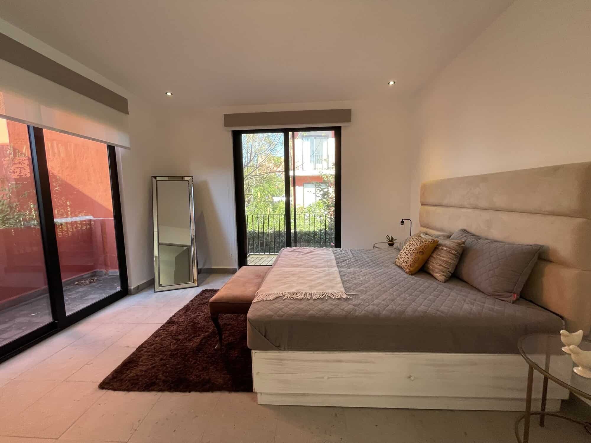 Spacious bedroom with modern decor, large windows, and access to a private balcony.