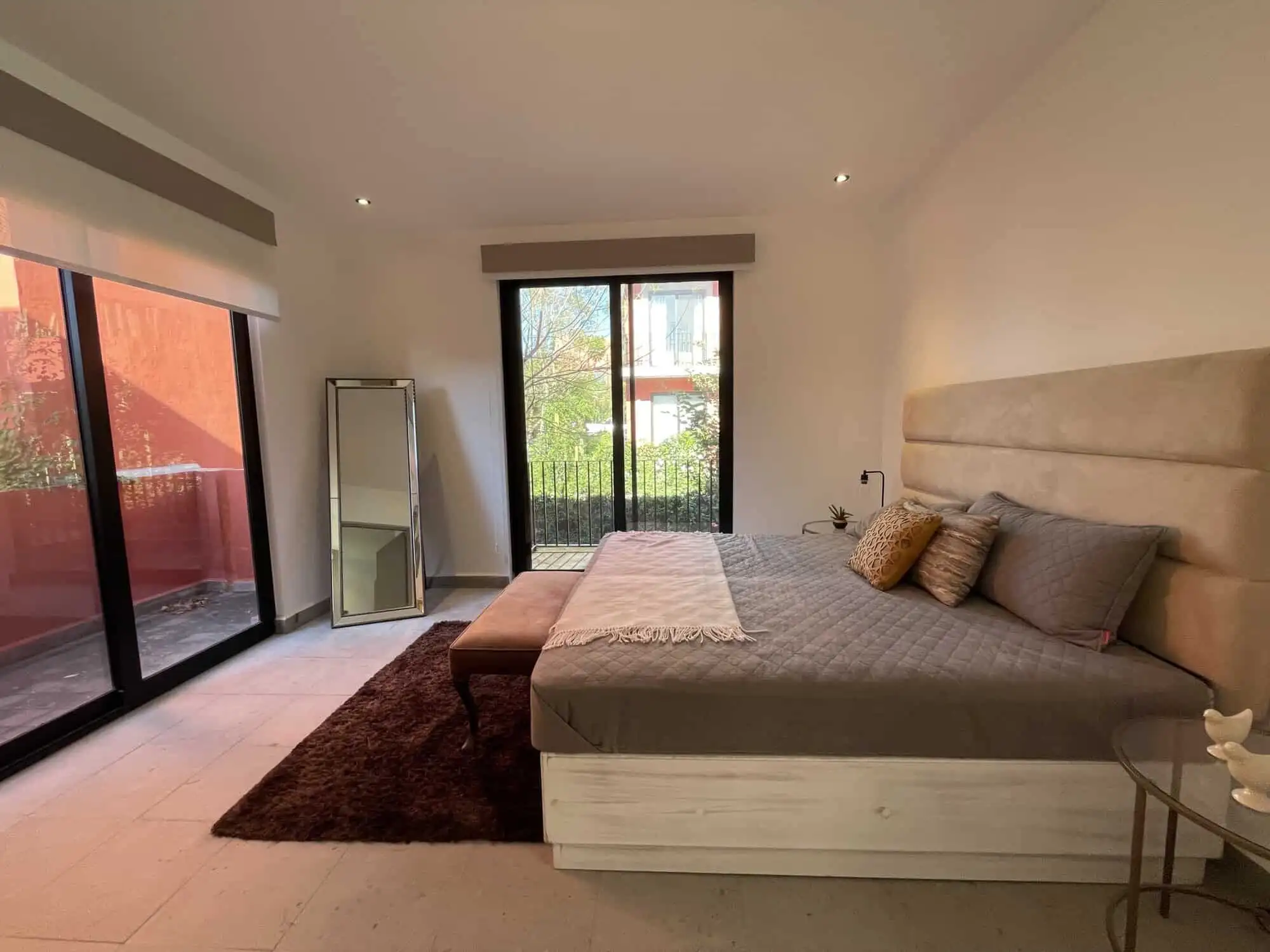 Spacious bedroom with modern decor, large windows, and access to a private balcony.