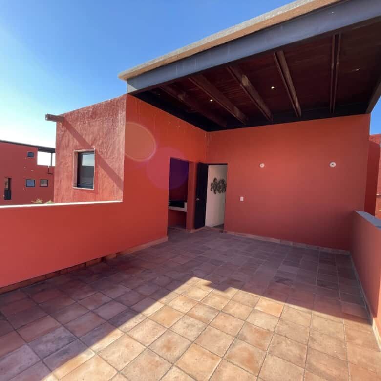 Spacious rooftop terrace with vibrant red walls and shaded area, perfect for relaxing and entertaini.