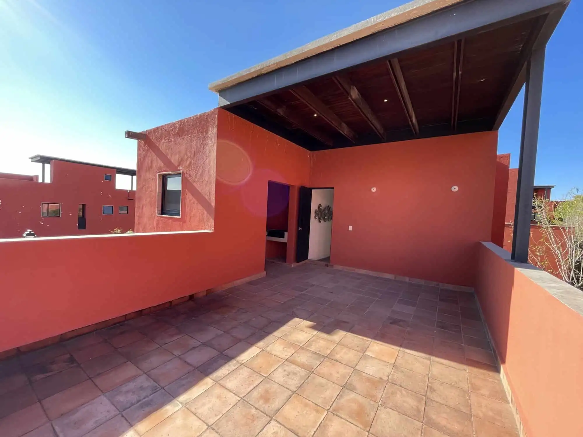 Spacious rooftop terrace with vibrant red walls and shaded area, perfect for relaxing and entertaini.