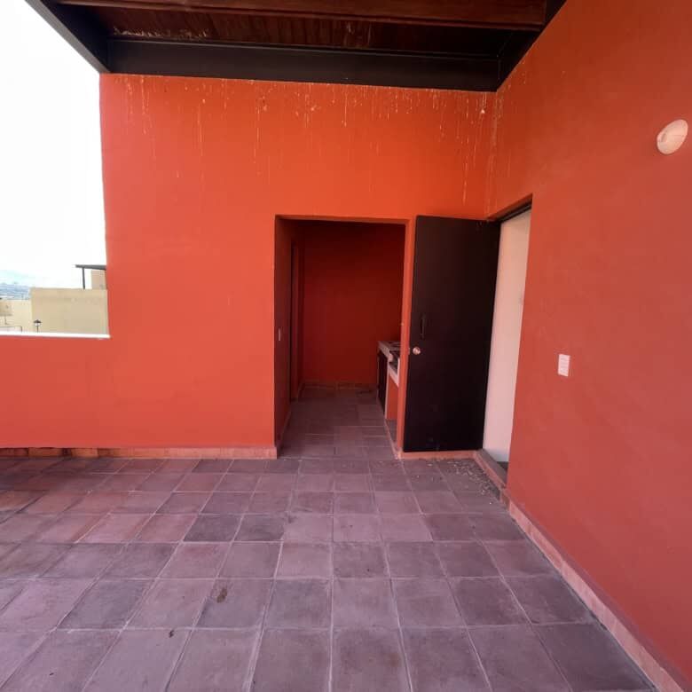 Spacious rooftop terrace with vibrant red walls and city views in Punta de Cielo, San Miguel de Alle.