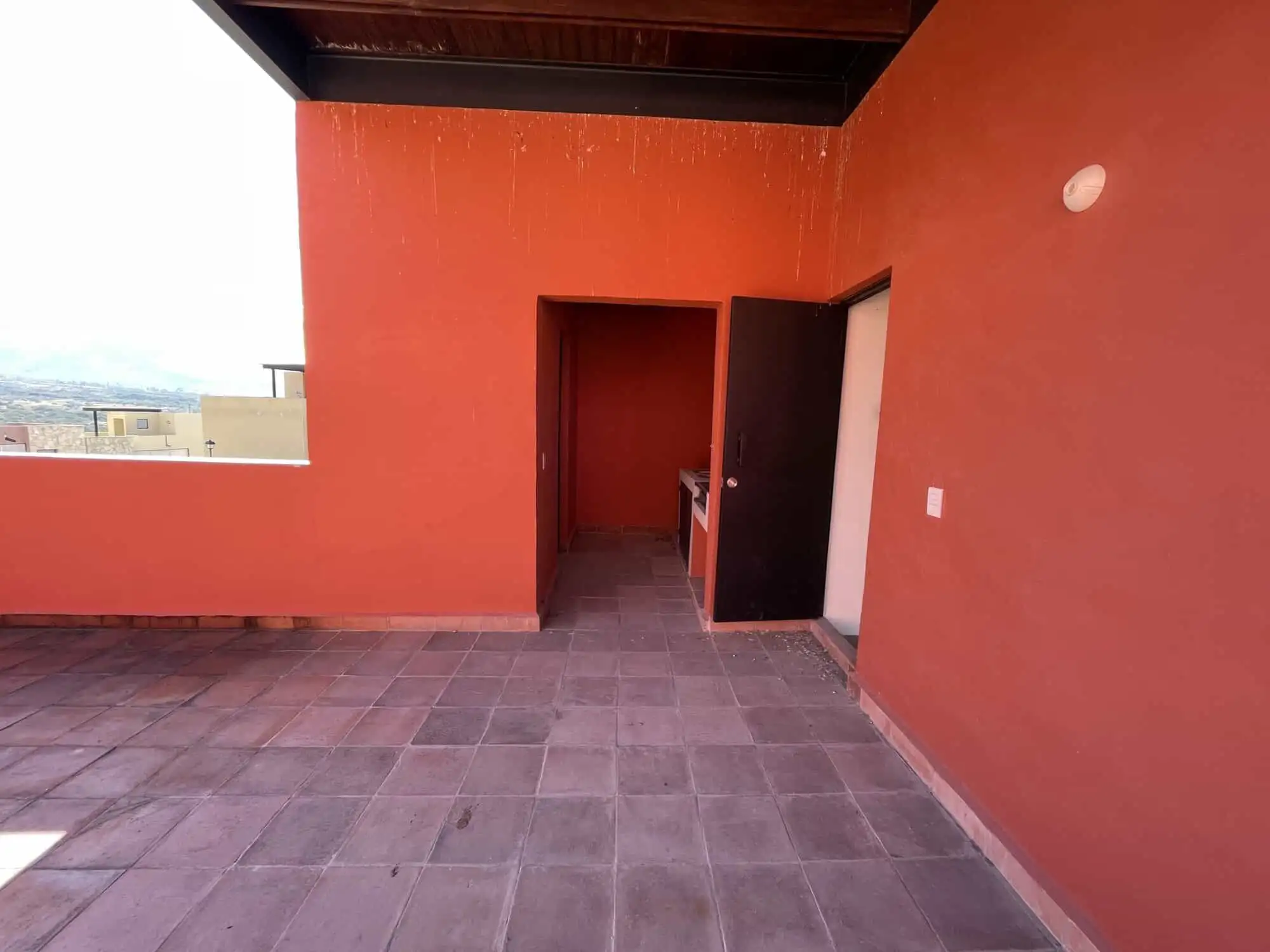 Spacious rooftop terrace with vibrant red walls and city views in Punta de Cielo, San Miguel de Alle.