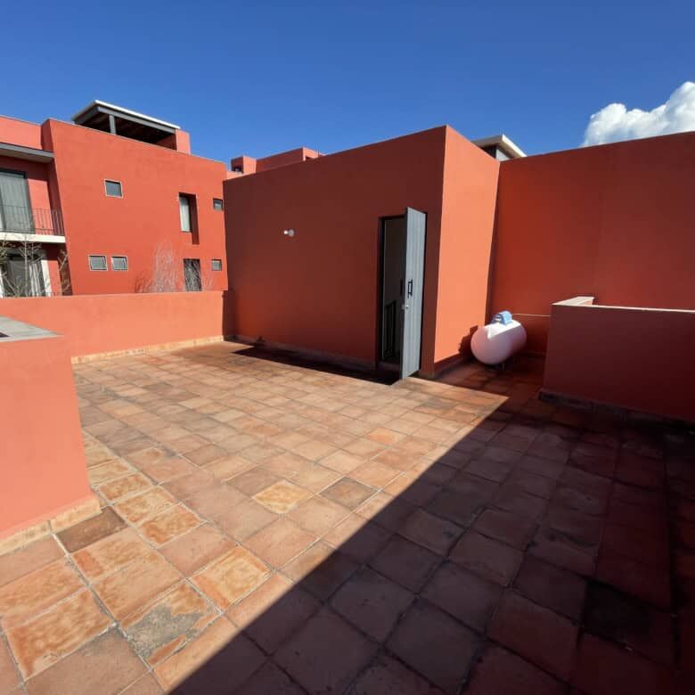 Spacious rooftop terrace with vibrant red walls, perfect for relaxing and entertaining in Punta de C.