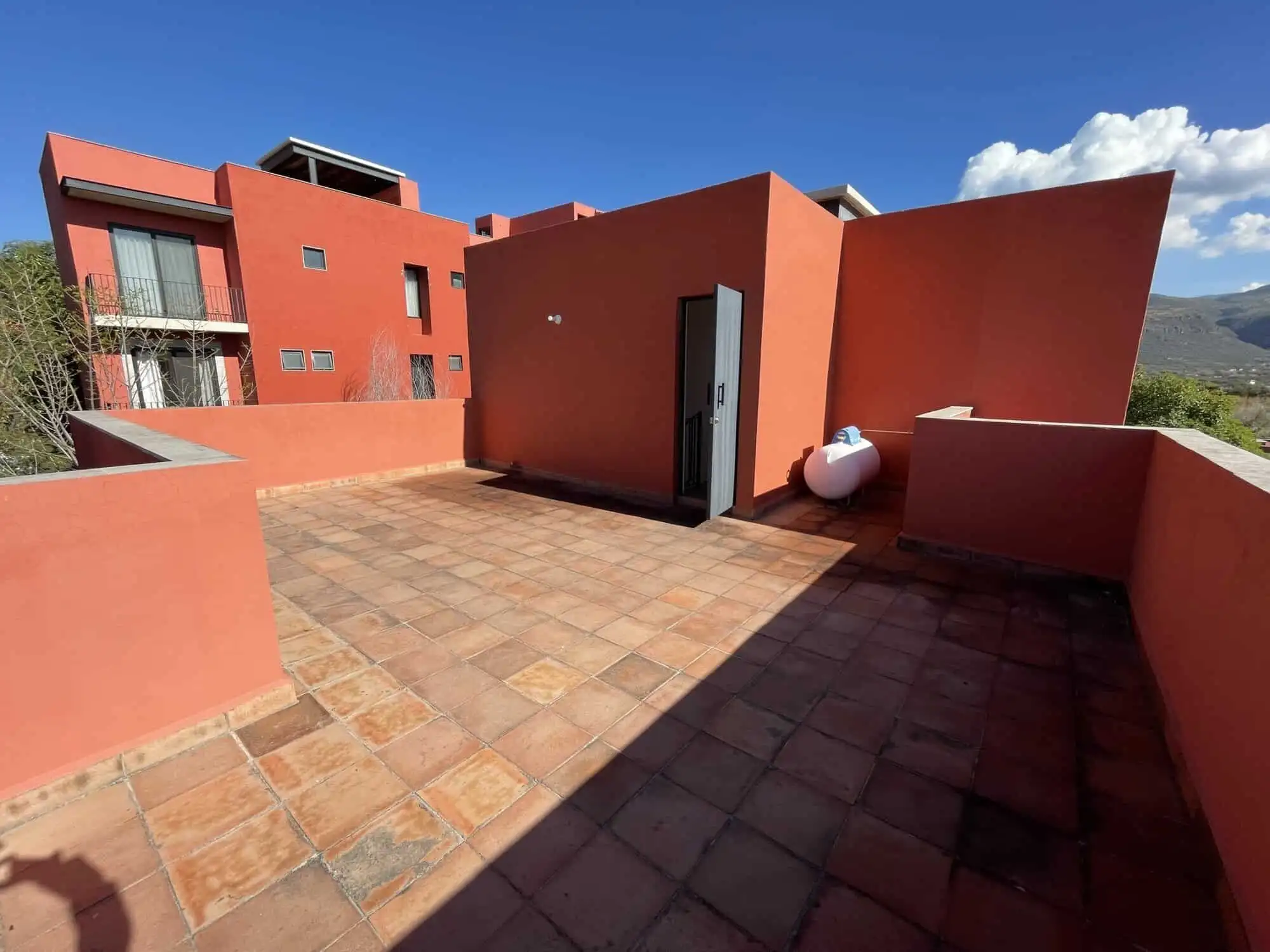 Spacious rooftop terrace with vibrant red walls, perfect for relaxing and entertaining in Punta de C.