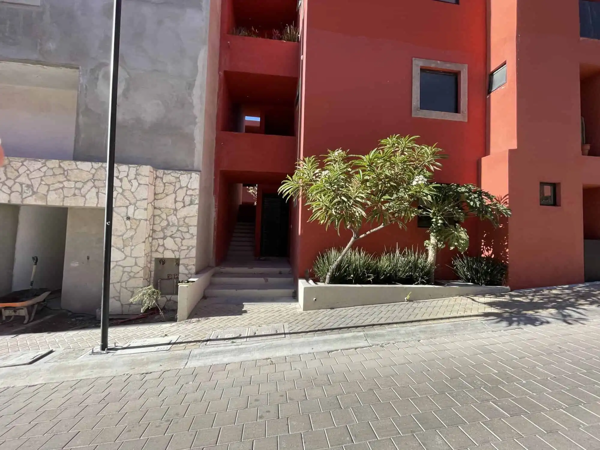 Floor home with vibrant red exterior in San Miguel de Allende, featuring lush greenery and contempor.