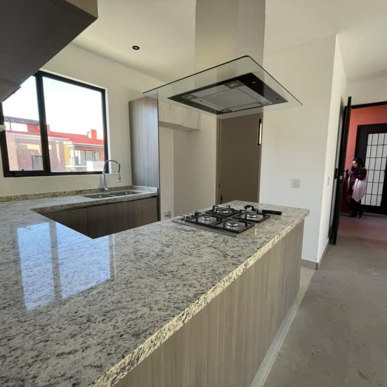 Luxury penthouse kitchen with granite countertops and large window views.