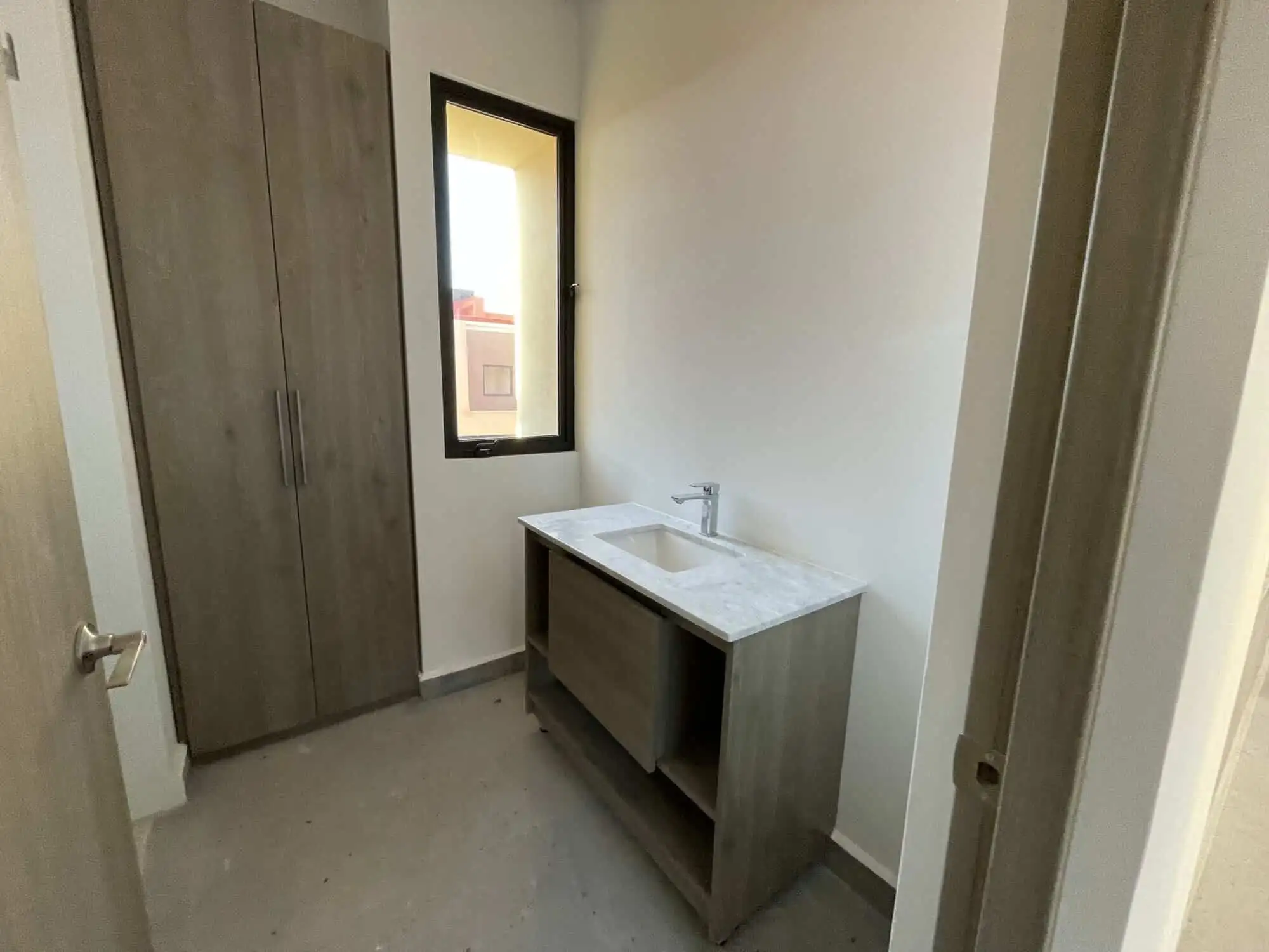 Modern laundry room with storage cabinet and window in San Miguel de Allende. Bright laundry space featuring a sleek cabinet and natural light from the window.