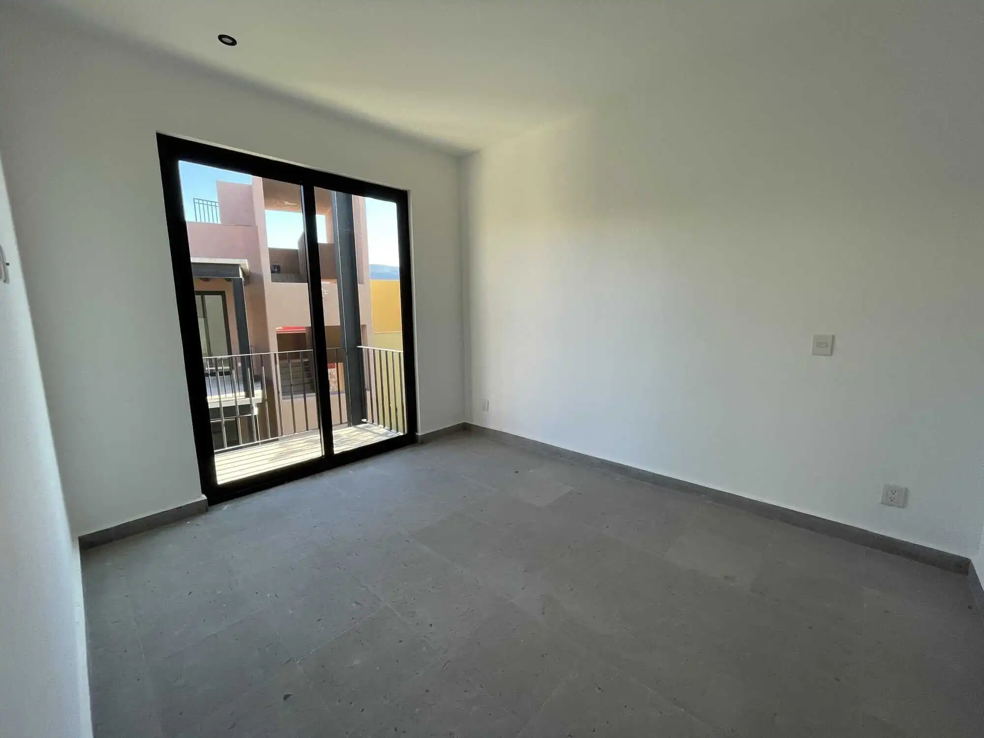 Modern living room with balcony access in San Miguel de Allende Spacious interior with large sliding glass doors opening to a balcony in a penthouse condo.