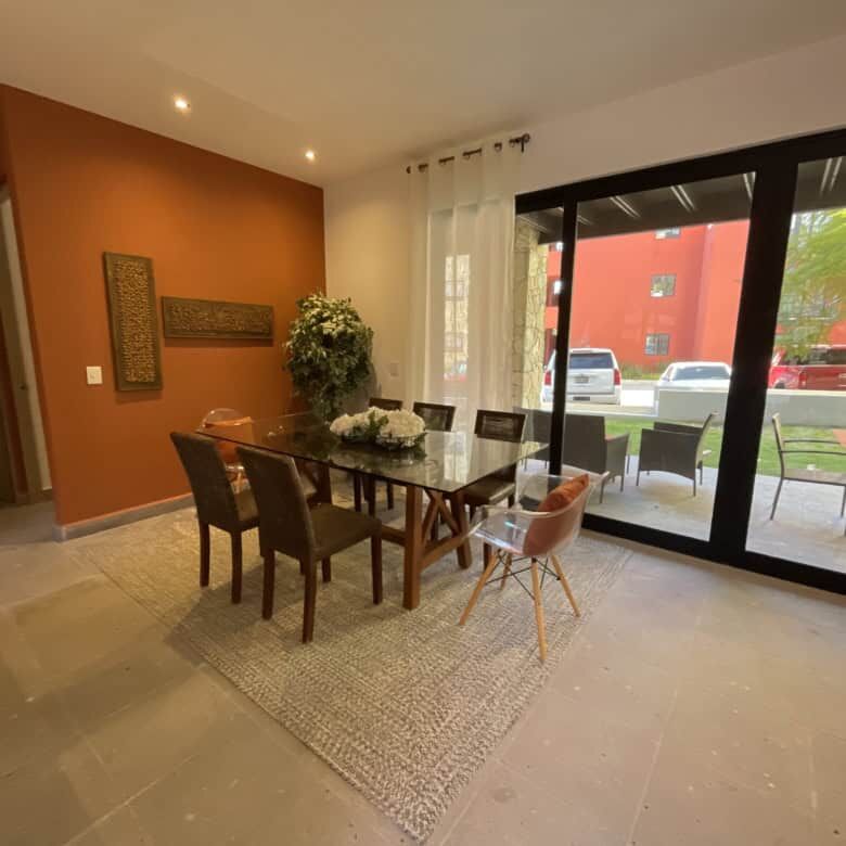 Spacious dining area with glass doors opening to outdoor patio, natural light, and contemporary deco.