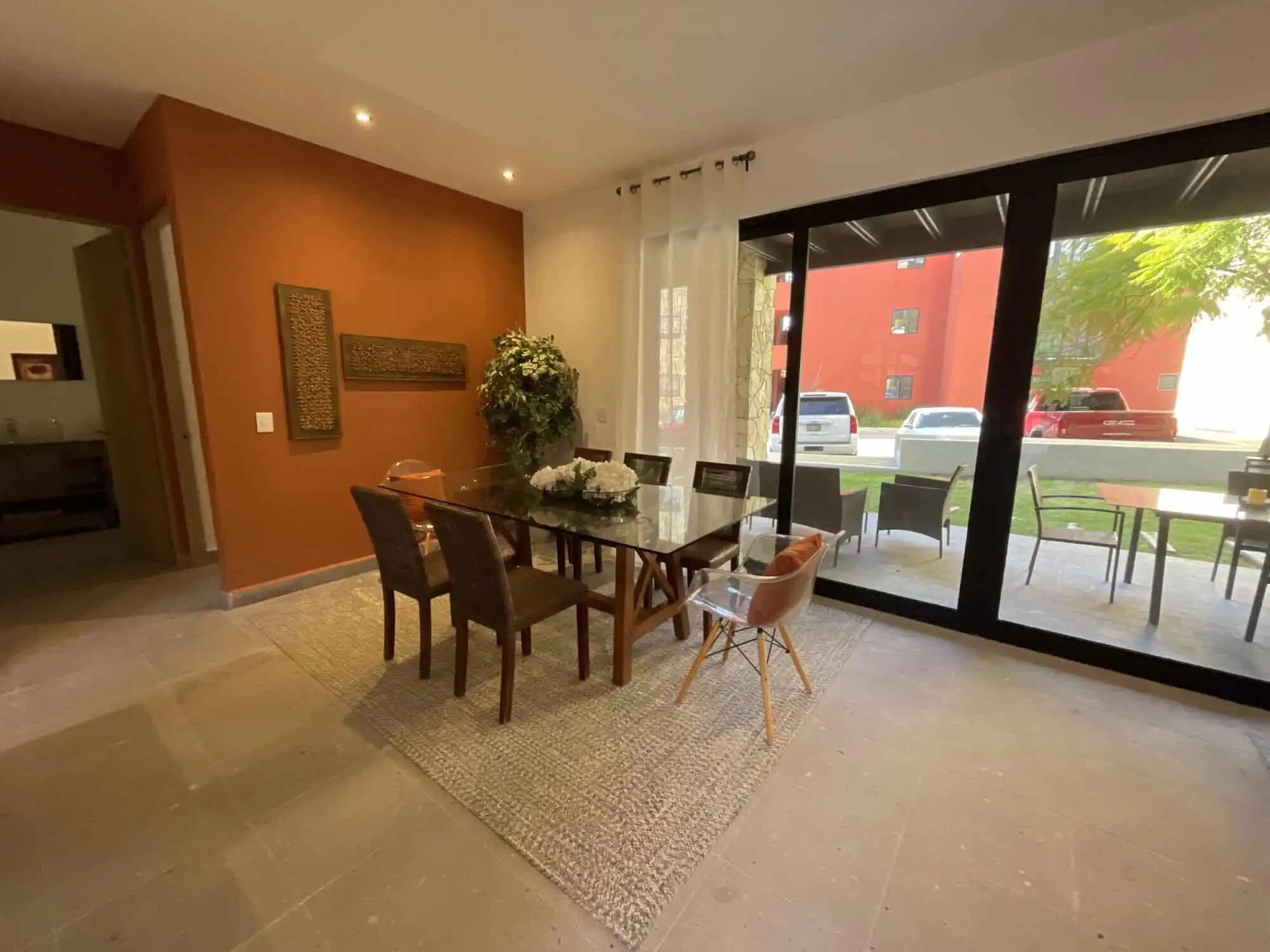 Modern dining room with large glass doors and outdoor patio view Spacious dining area with glass doors opening to outdoor patio, natural light, and contemporary deco.