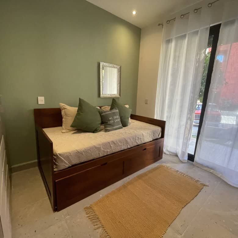 Bright bedroom with green accent wall and natural light from large window.
