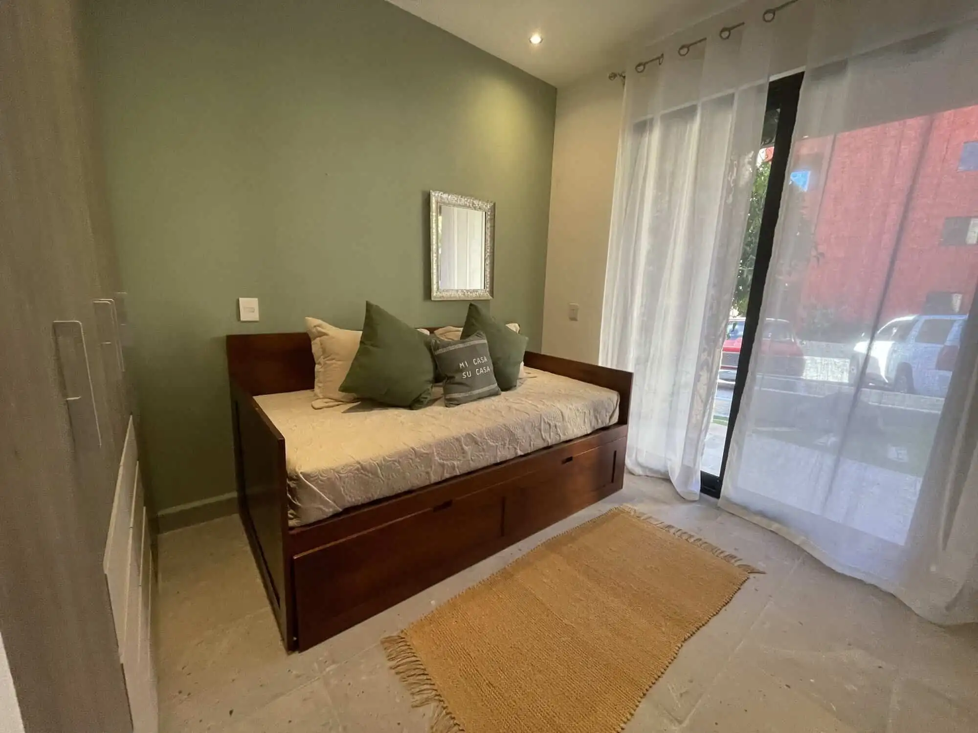 Cozy Bedroom with Green Wall Bright bedroom with green accent wall and natural light from large window.