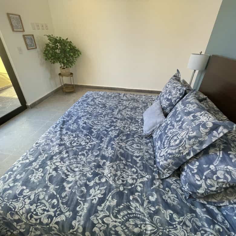 Spacious bedroom with elegant blue and white bedding, modern decor, and natural light in Punta del C.