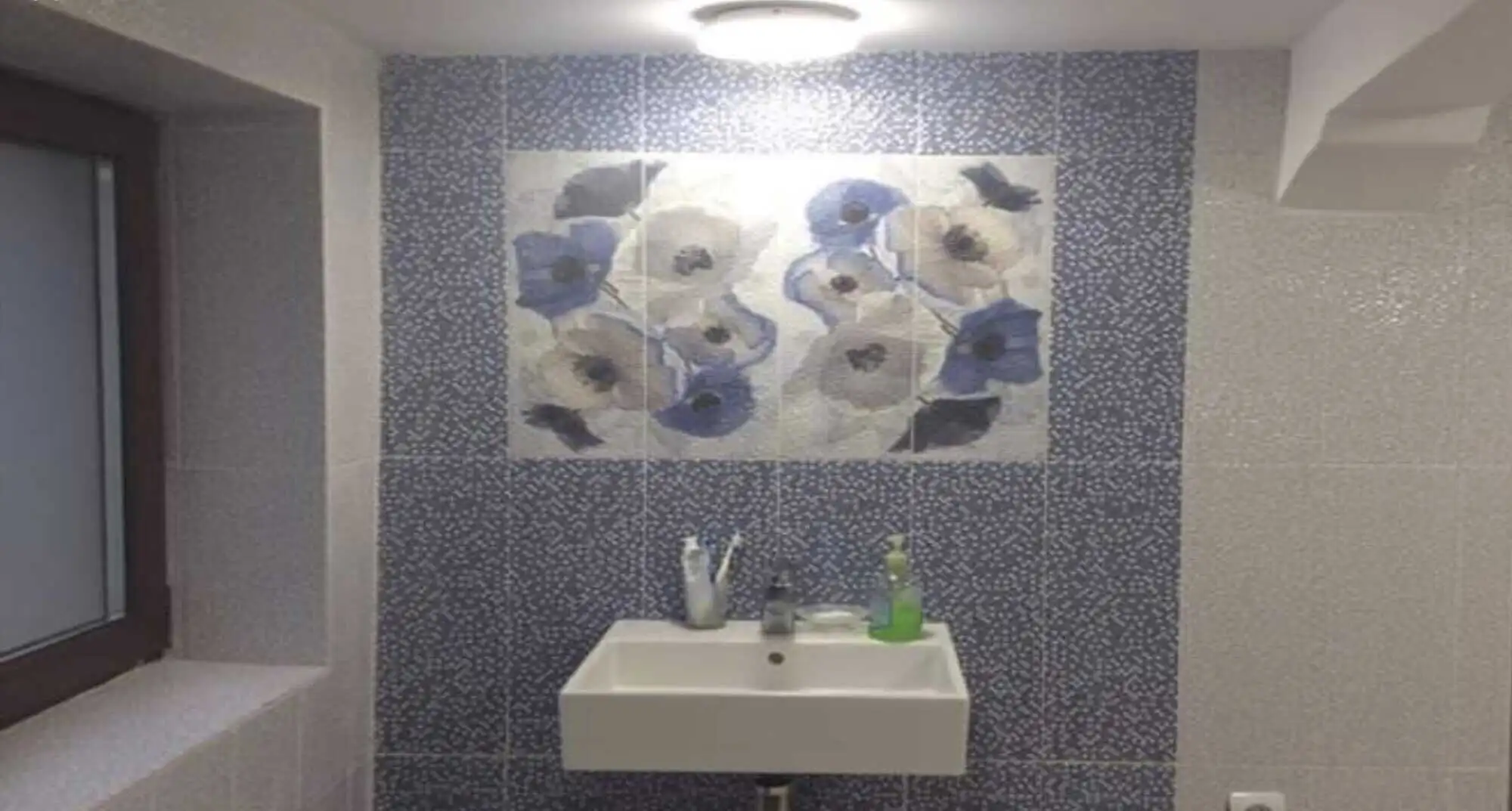 Bright bathroom featuring a blue floral mural, white sink, and natural light from the window.