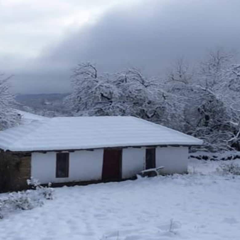 Traditional cottage covered in snow in Rogulyat Mlechevo, Bulgaria.