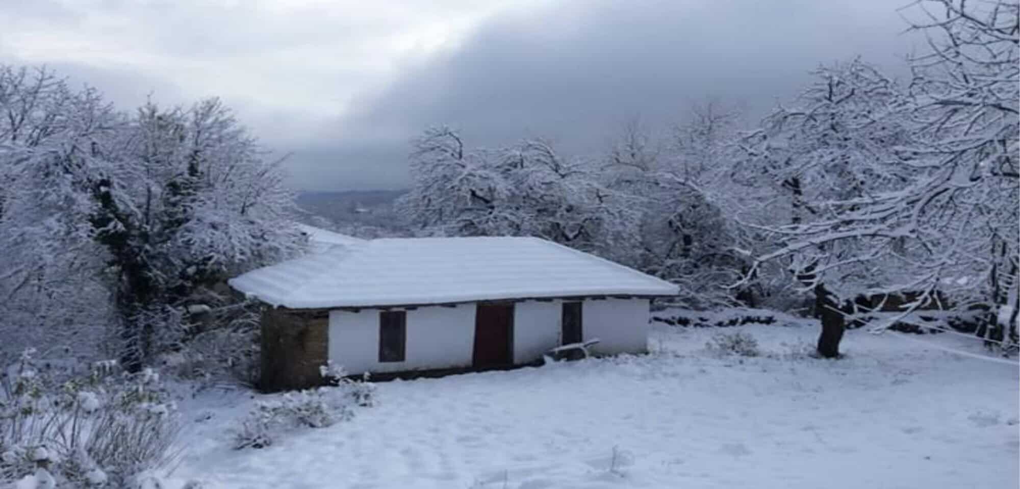 Traditional cottage covered in snow in Rogulyat Mlechevo, Bulgaria.