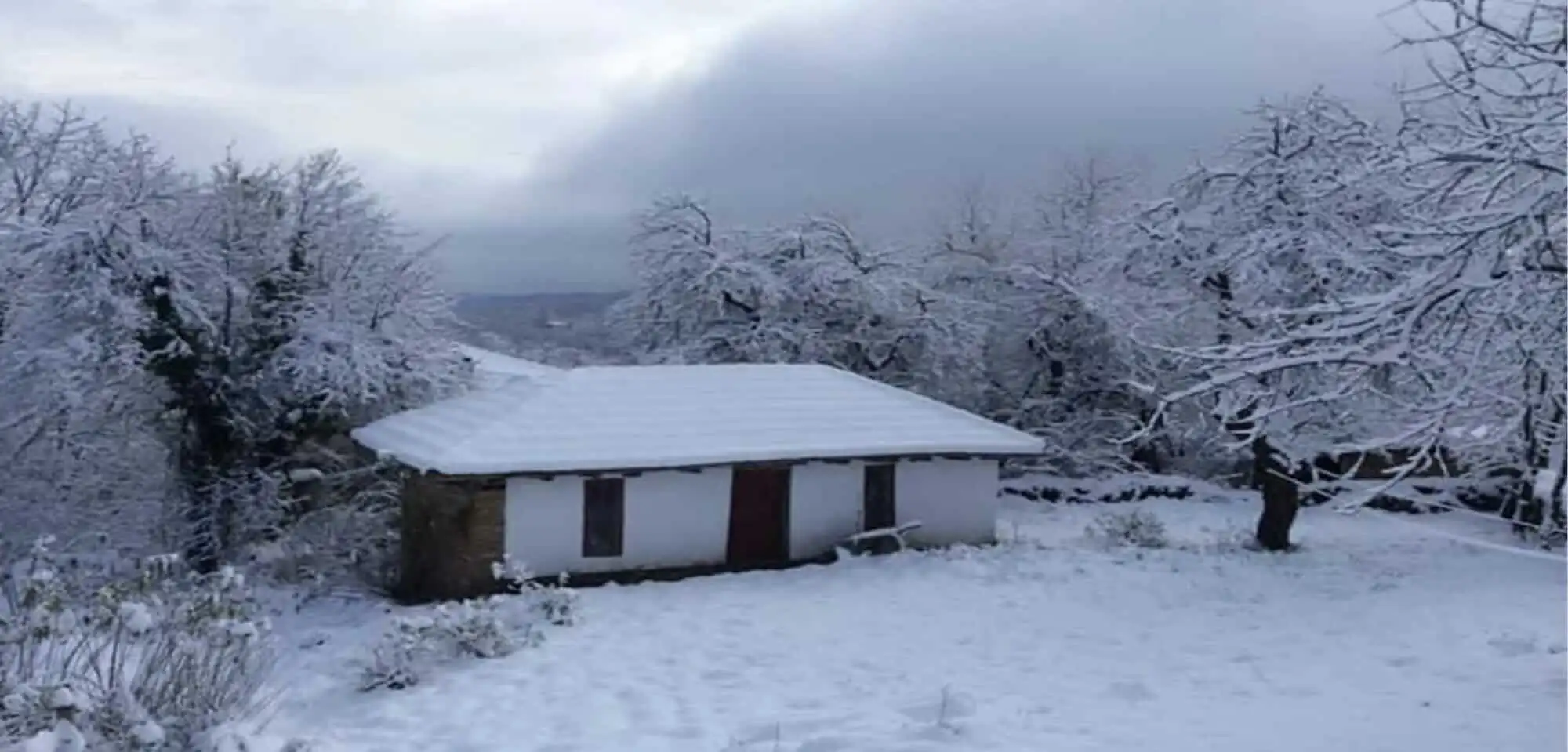 Traditional cottage covered in snow in Rogulyat Mlechevo, Bulgaria.