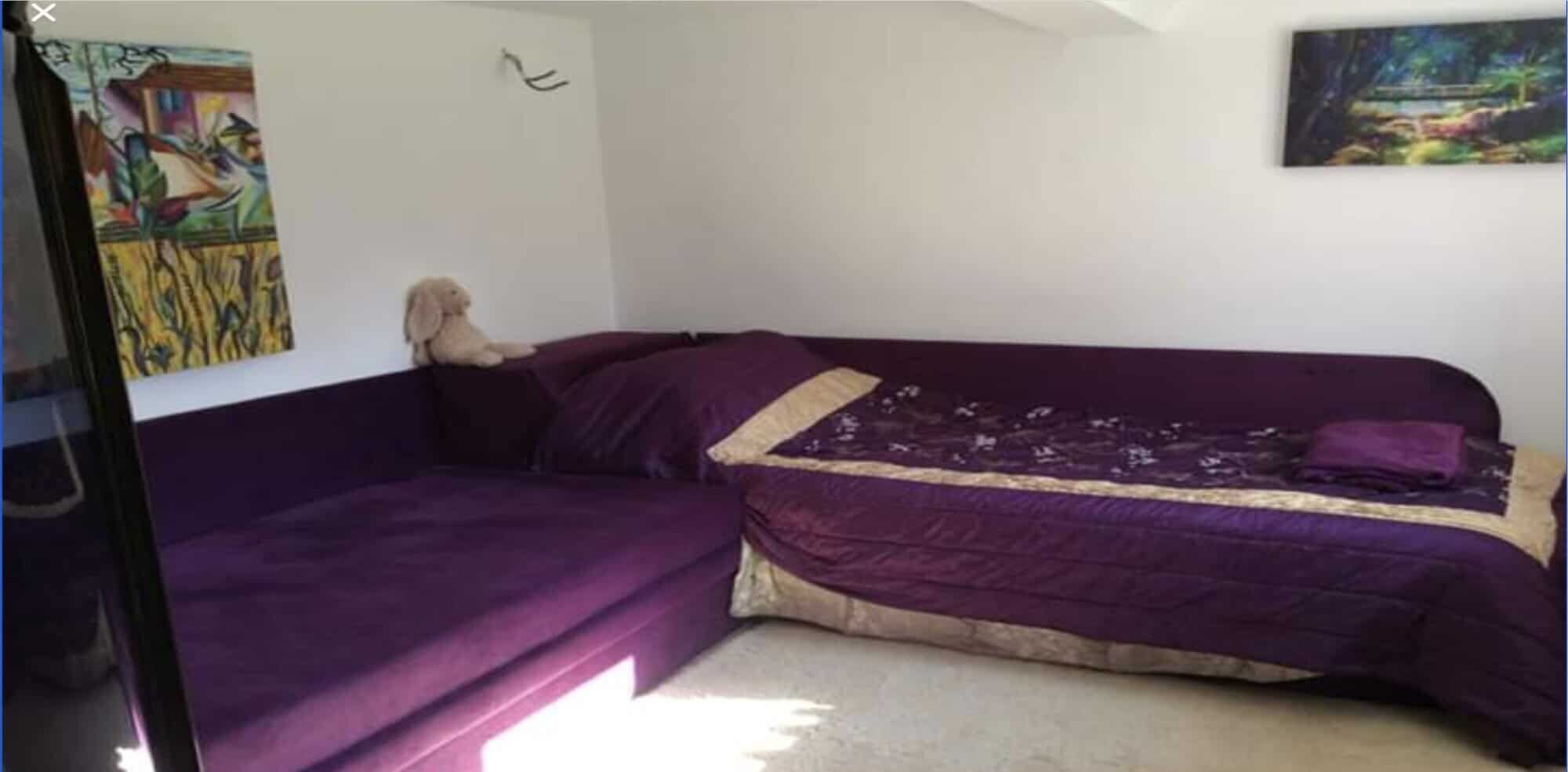 Interior view of a bedroom featuring purple beds and colorful wall art.