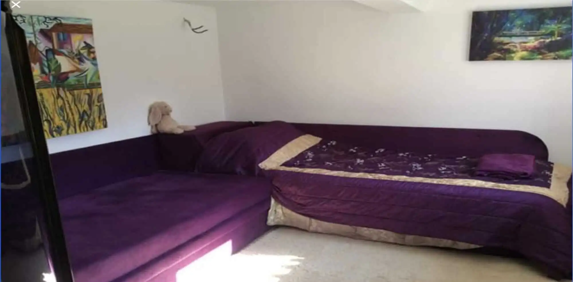 Interior view of a bedroom featuring purple beds and colorful wall art.