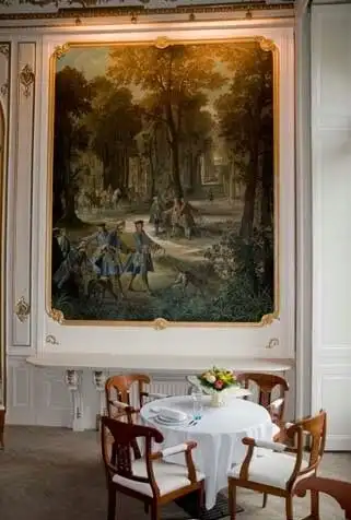 Château interior with classic decor and a large landscape painting.