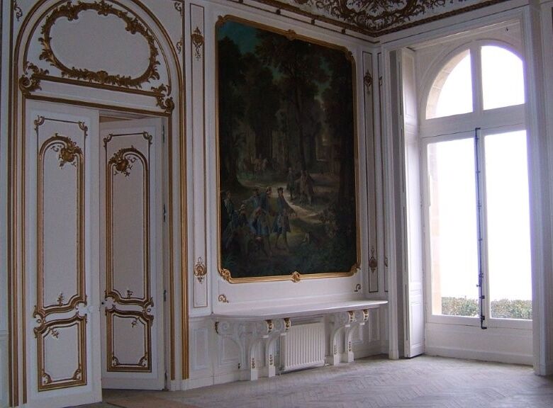 Luxurious château interior featuring ornate gold-trimmed walls, a large window, and classical furnis.