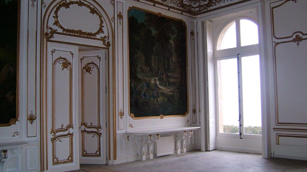 Elegant Château Interior with Classic Decor and Large Window Luxurious château interior featuring ornate gold-trimmed walls, a large window, and classical furnis.