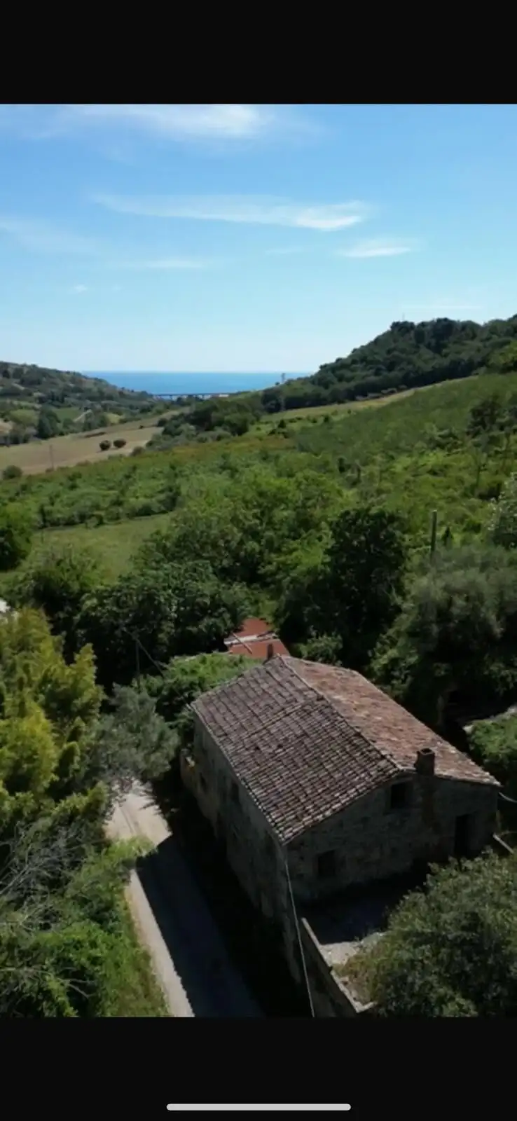 Rustic farmhouse surrounded by lush greenery with distant sea view in Campofilone, Fermo.