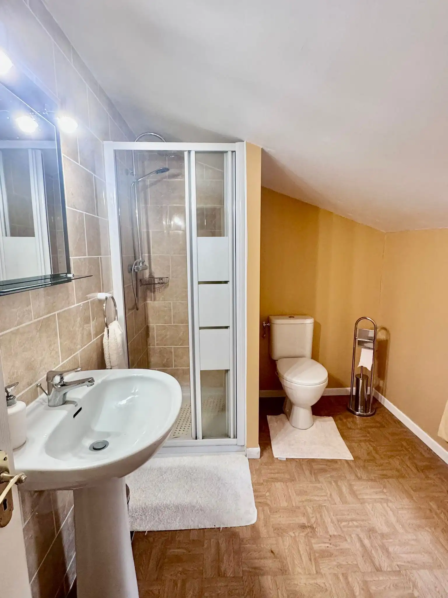 Bright bathroom featuring a shower enclosure, toilet, and sink in a modern setting.