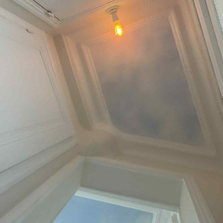 Bright view from a Paris apartment window with a warm ceiling light.