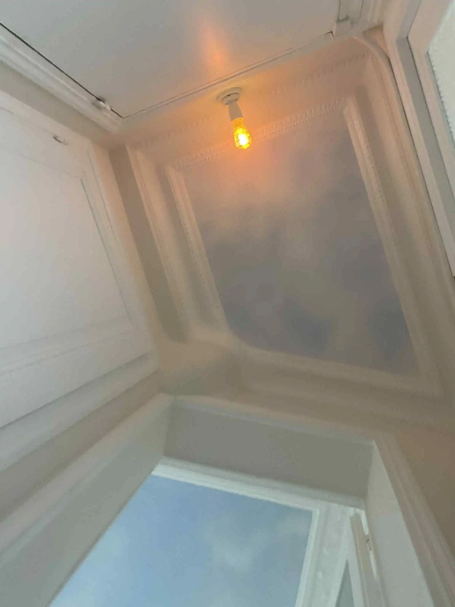 Bright view from a Paris apartment window with a warm ceiling light.
