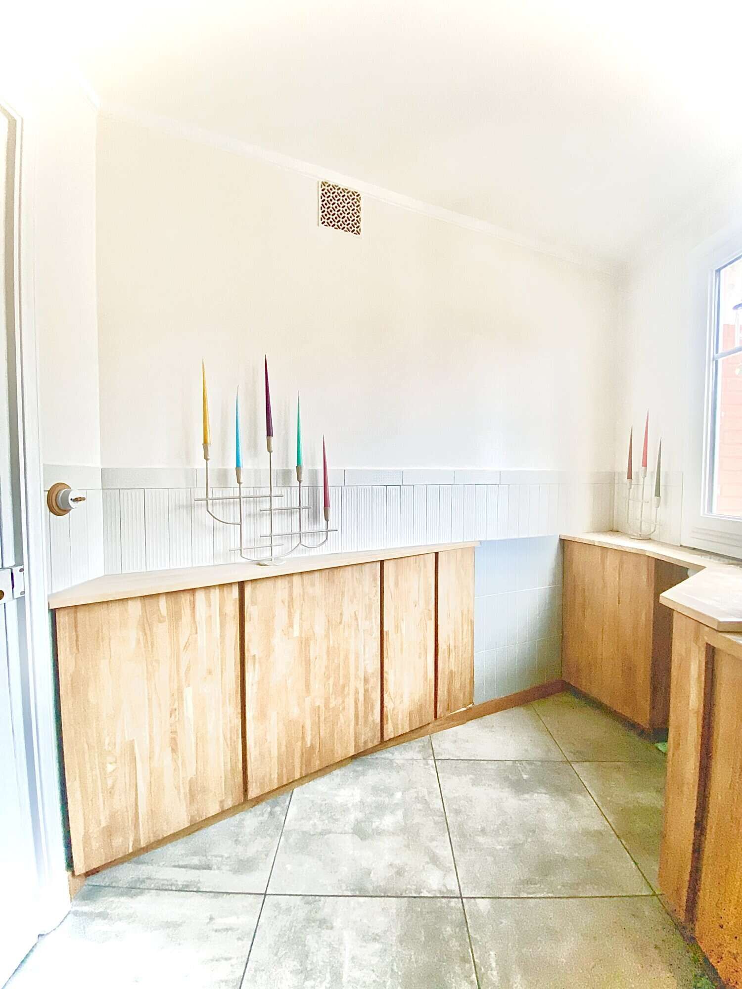 Modern kitchen with wooden cabinets and colorful candles in Paris apartment.