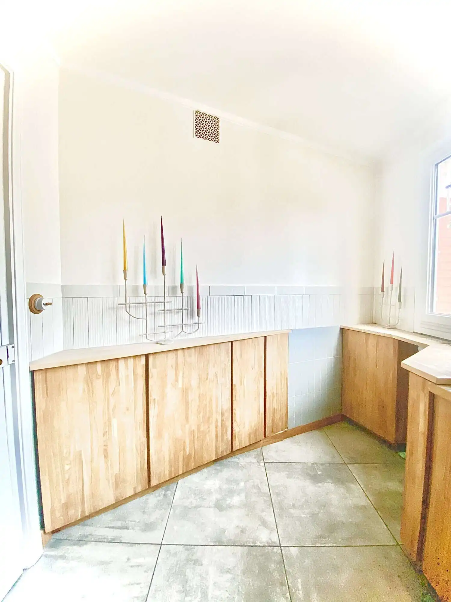 Modern kitchen with wooden cabinets and colorful candles in Paris apartment.