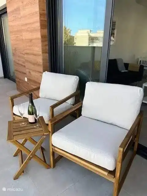 Balcony with two wooden chairs and a small table, perfect for relaxing in Santiago De La Ribera Murc.