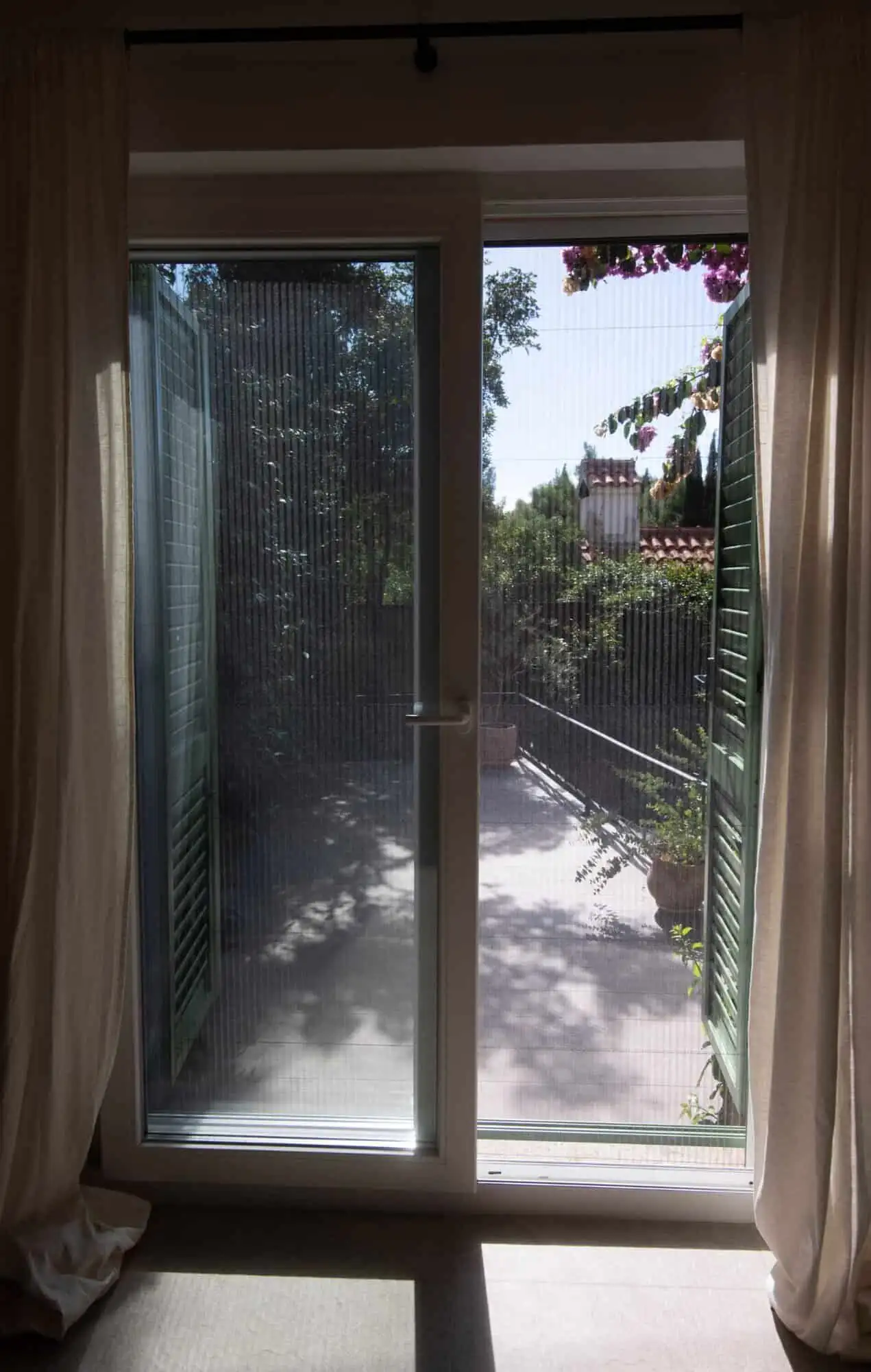 Modern sliding glass door opening to balcony in high-end Split home Sliding glass door to balcony with lush greenery view in Split.