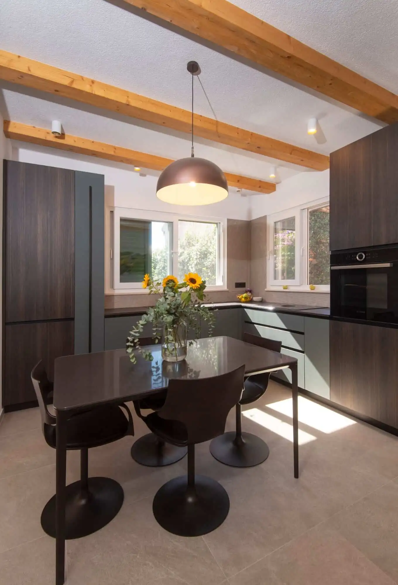 Modern kitchen with wooden ceiling beams and black furniture in Split home Modern kitchen with wooden ceiling beams, black cabinetry, and a dining area with a vase of sunflowe.