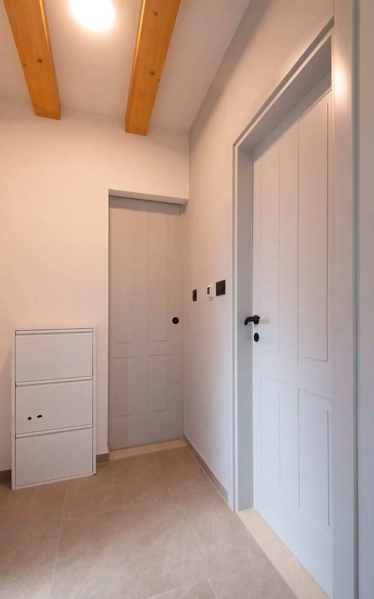 Modern interior hallway with white doors and wooden ceiling beams. Bright hallway featuring white doors and minimalist decor in a high-end Split residence.